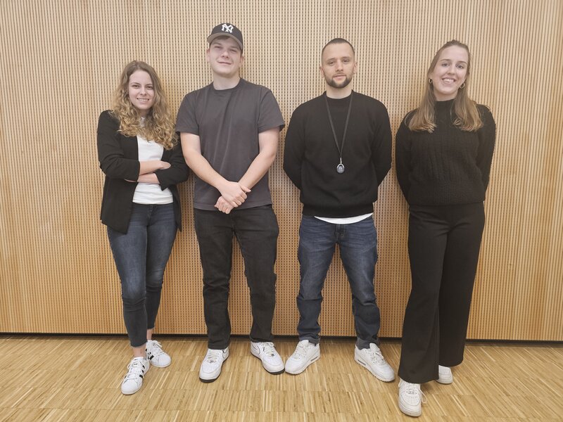 Studi-Coaches vor einer Holzwand