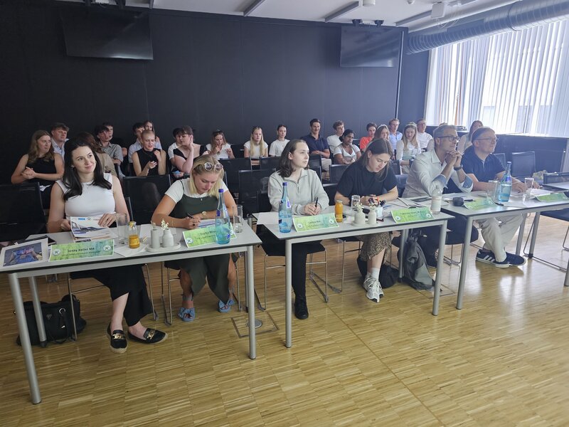 Jury sitzt in vorderster Reihe nebeneinander am Tisch